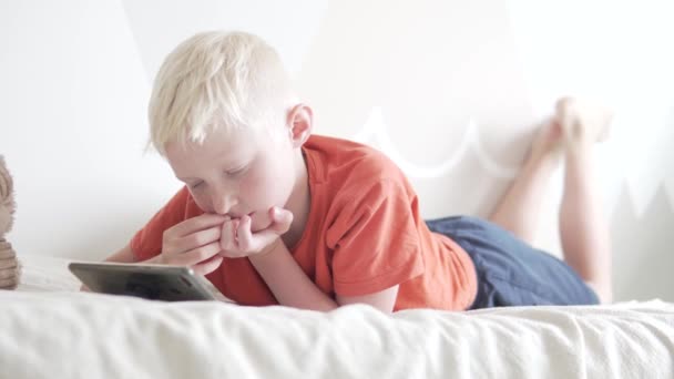 Красивий хлопчик-підліток використовує мобільний телефон вдома в ліжку — стокове відео