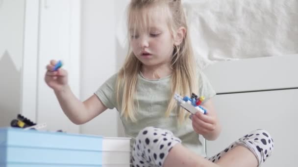 En liten flicka spelar en designer gjord av färgade små detaljer — Stockvideo
