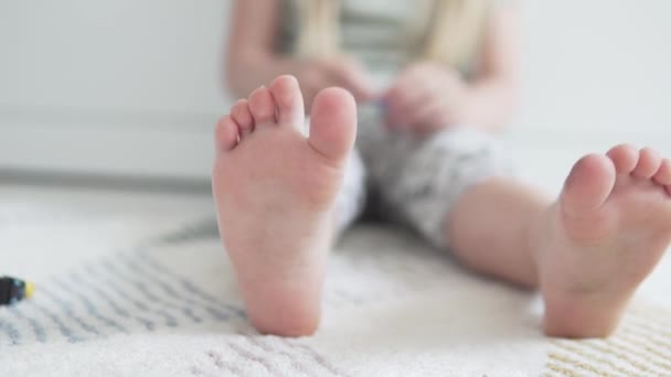 Um close-up dos pés das crianças jogando o designer da casa no chão — Vídeo de Stock