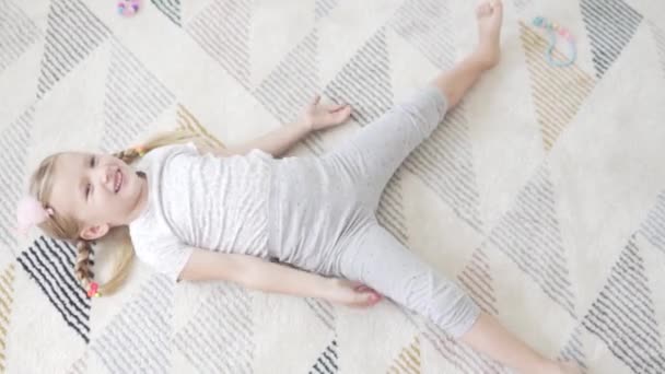Een schattig klein meisje doet een leuke ochtend opladen thuis op het tapijt — Stockvideo