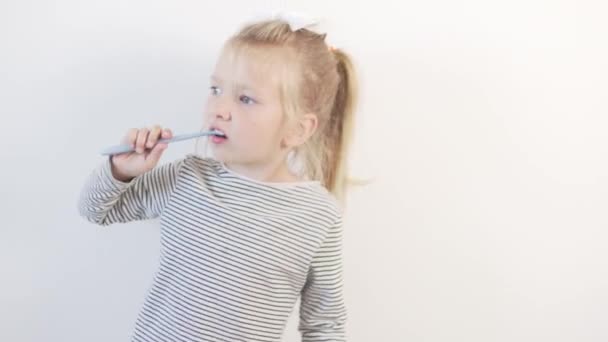 Egy vicces kislány fogat mos egy fogkefével és táncol. — Stock videók