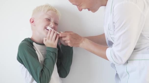 歯医者はブロンドの歯ブラシで男の子の敏感な歯を磨く — ストック動画