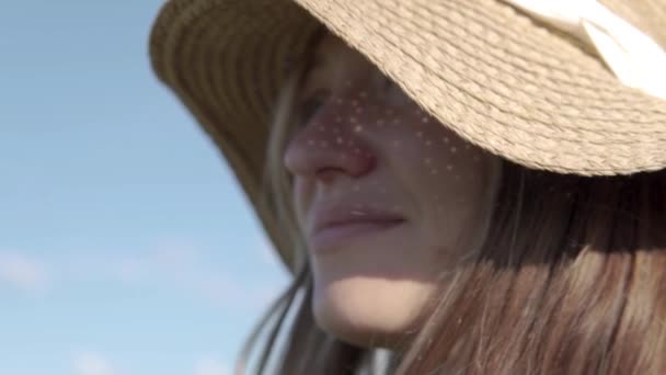 Close-up do rosto de uma mulher bonita em um chapéu de palha ao sol — Vídeo de Stock