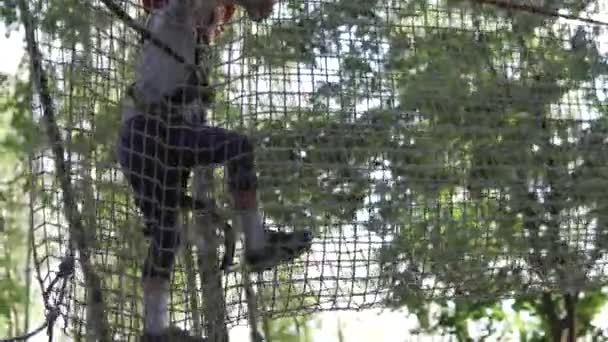 Una niña pasa un carril de obstáculos en un parque de cuerdas — Vídeo de stock