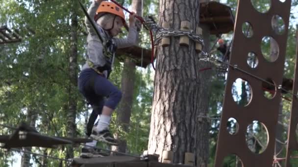 A happy little girl passes obstacles in the rope park of attractions. — Stock Video