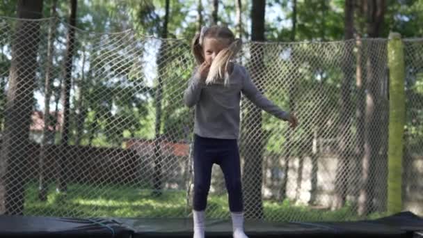 Menina feliz salta em um trampolim no verão no parque — Vídeo de Stock