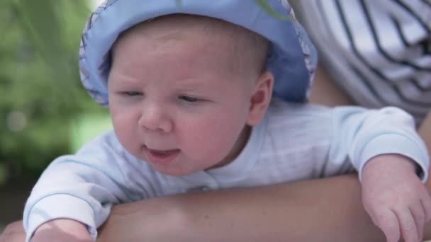 Een moeder houdt een kleine baby in haar armen tijdens een wandeling in het park — Stockvideo