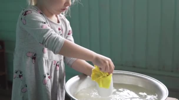 Schattig klein meisje wast naar modder een kopje in de trog met water op dace. — Stockvideo