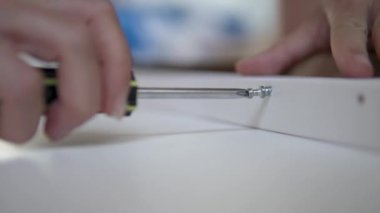 Kadınların elleri sürgüyü tornavidayla beyaz mobilyalara çevirir.