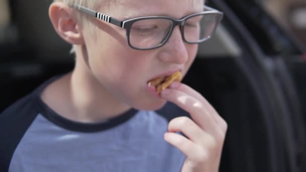 Rapaz ganancioso enfia na boca o último pedaço de sanduíche . — Vídeo de Stock