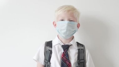 Okulda yüzünde tıbbi maske olan güzel bir okul çocuğu.