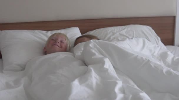 Cute children boy and girl rest in bed in a hotel room while on vacation — Stock Video