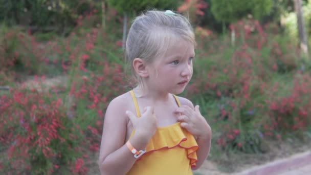 Close-up of a beautiful little girl in a swimsuit against the background of a green park — Stock Video