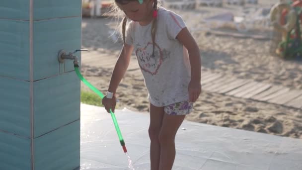 Słodka dziewczyna myje nogi z piasku pod prysznicem na plaży w lecie — Wideo stockowe