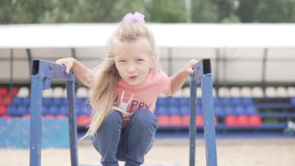 Mała dziewczynka siedzi na podium sędziów do siatkówki plażowej. — Wideo stockowe