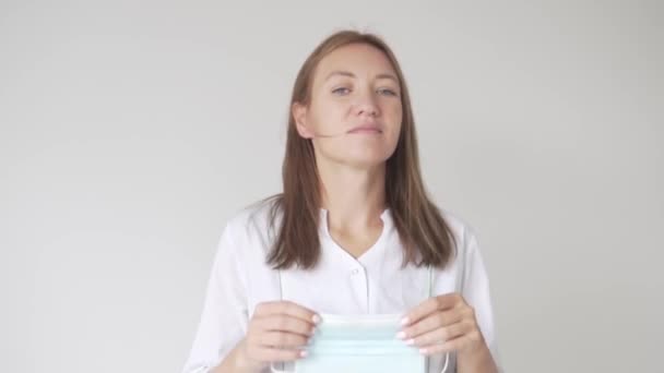 Eine schöne Krankenschwester setzt sich eine medizinische Maske über ihr Gesicht — Stockvideo