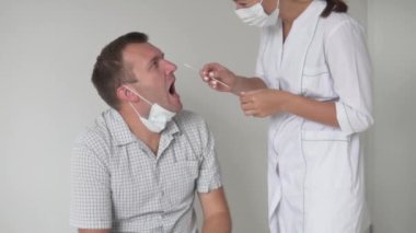 Doktor, yurtdışından dönen bir turistten koronavirüsten örnek alıyor.
