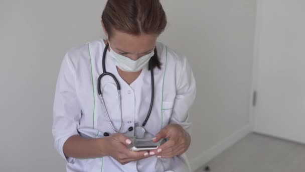 Egy női orvos tárcsáz egy üzenetet a telefonján. — Stock videók