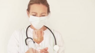 Tıbbi maskeli bir kadın doktor elinde büyük bir kum saati tutuyor.