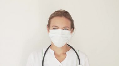 Yüzünde tıbbi maske olan güzel bir kadın doktorun yakın çekimi.