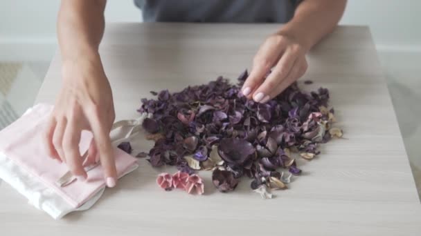 말린 꽃을 넣어 장식용 자루를 싸는 일을 마무리하는 모습 — 비디오