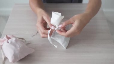 Kadın eli, aromalı iç çamaşırına bir kese kuru çiçekle şık bir çanta bağlar.