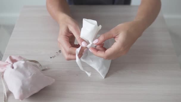 Kvinnors händer binder en elegant väska med dospåse med torra blommor till smakunderkläder — Stockvideo