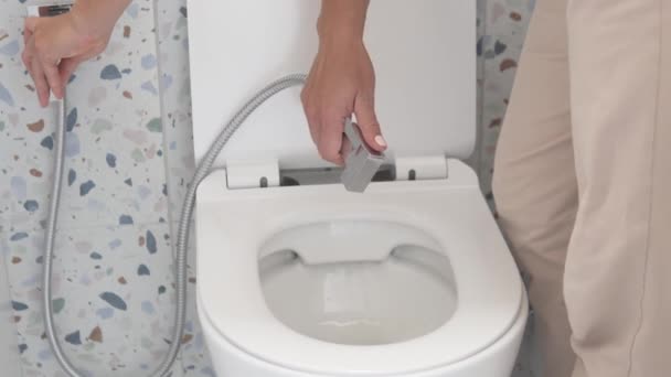 Uma mulher lava o banheiro com um chuveiro higiênico. — Vídeo de Stock