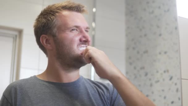 Przystojny gej człowiek myje jego zęby w w w rano w w łazienka — Wideo stockowe