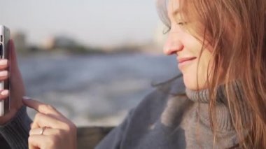 Güzel bir kadın St. Petersburg kanallarında teknelerde yüzüyor ve telefonda selfie çekiyor.