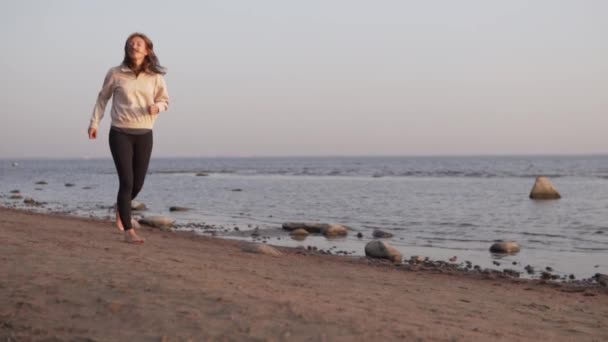 一个漂亮的女人沿着海岸线奔跑，慢动作射击，预先打滚的灯光 — 图库视频影像