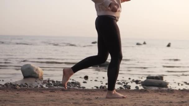 Медленная съемка Женщина бежит босиком по морю на закате в прохладный осенний день — стоковое видео