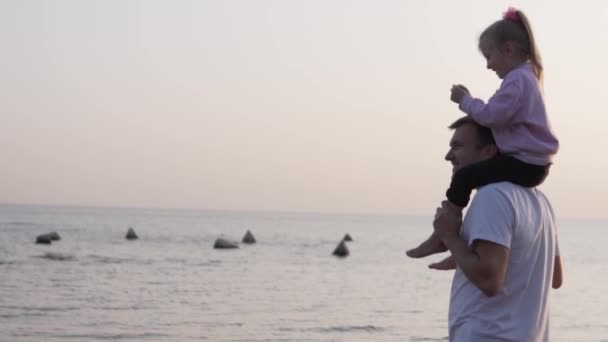 Papà tiene la figlioletta sulle spalle e guardano il mare e il tramonto — Video Stock