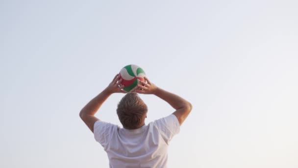 Un hombre entrena para jugar voleibol en la playa. — Vídeo de stock