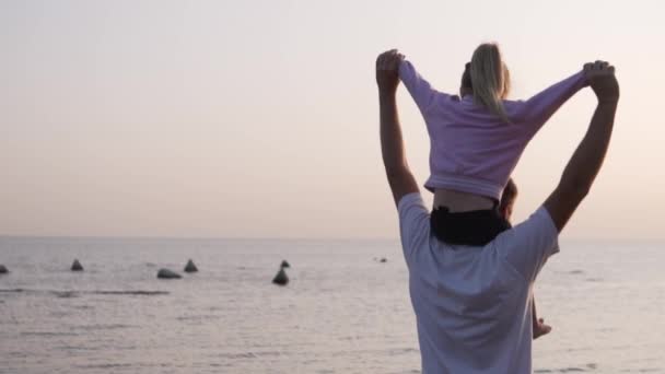 Pappa håller en liten dotter vid havet på sina axlar på hösten.. — Stockvideo