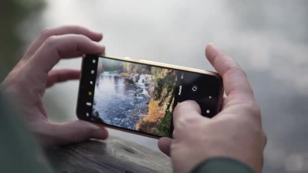 Крупный план мужских рук с телефоном делает фотографию красивой осенней природы — стоковое видео