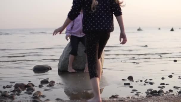Bir kızın iki kız arkadaşı gün batımında deniz kenarında oynuyorlar. — Stok video