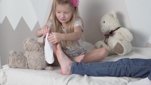 Η μικρότερη αδελφή με χαρά βάζει κάλτσες στον μεγαλύτερο αδερφό. — Αρχείο Βίντεο