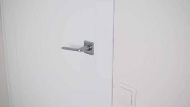A fehér ajtó krómozott ajtókilincsének közelsége — Stock videók