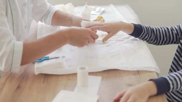 En kvinnlig läkare gör ett finger bandage till en tonåring pojke — Stockvideo