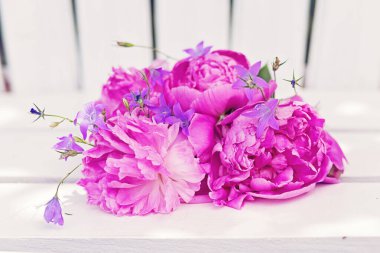 Beyaz ahşap bir sandalyeye yerleştirilmiş büyük pembe çiçekler..