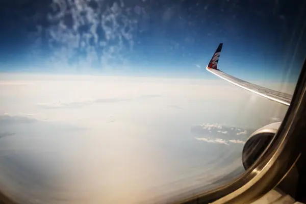 空と雲と翼で汚れた窓を飛行機から空撮 — ストック写真