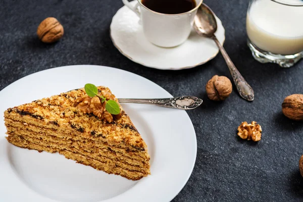 Traditional dessert honey cake with walnut and with coffee on dark stone table