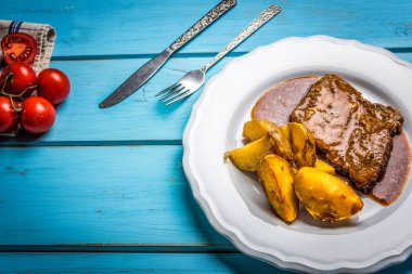 Izgara domuz biftek ve kızarmış patates mavi masada beyaz plaka üzerinde