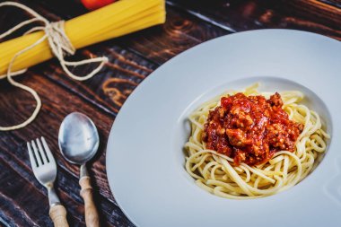 Geleneksel İtalyan makarna spagetti bolognesse kıyma ve domates ve koyu ahşap masa üzerinde ham spagetti