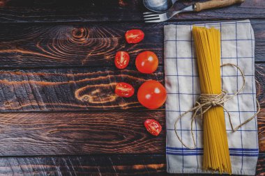 Ham İtalyan makarna spagetti ve koyu ahşap masa üstüne domates görüntülemek