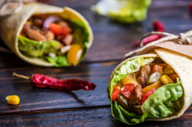 Geleneksel Meksika tortilla şal koyu ahşap masa üzerinde ızgara tavuk eti ve sebze ile