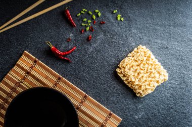 İle Asya anlık erişte ve kırmızı biber ve yeşil soğan ve siyah taş masada yemek çubukları