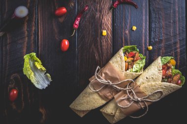 Geleneksel Meksika tortilla şal koyu ahşap masa üzerinde ızgara tavuk eti ve sebze ile