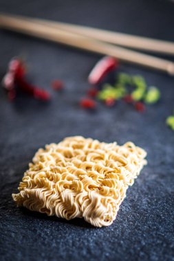 İle Asya anlık erişte ve kırmızı biber ve yeşil soğan ve siyah taş masada yemek çubukları